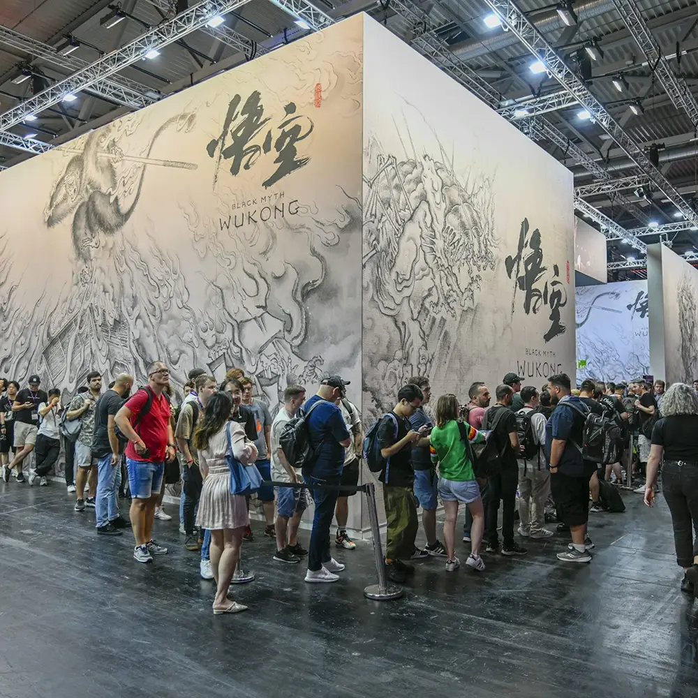 Gaming enthusiasts at the 2023 Gamescom gaming fair with Black Myth Wukong artwork behind them